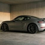 Porsche Cayman GT4 RS grise avec aileron fixe, garée dans un garage en béton