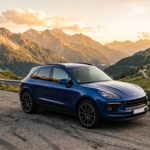 Porsche Macan S bleu sur une route de montagne au coucher du soleil