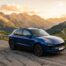 Porsche Macan S bleu sur une route de montagne au coucher du soleil