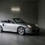 Porsche 996 Turbo Cabriolet grise, capote fermée, garée dans un garage moderne en béton