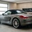 Porsche Boxster gris avec capote noire relevée, vue arrière trois-quarts dans un garage moderne