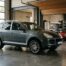Porsche Cayenne première génération garée dans un garage aux côtés d'une 911 classique