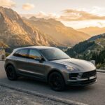 Porsche Macan gris sur une route de montagne au coucher du soleil