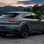 Porsche Macan gris vue arrière sur une route de montagne au crépuscule