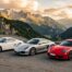 Trois Porsche Cayman de générations successives garées côte à côte sur une route de montagne