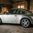 Porsche 911 argentée de la génération refroidie par air garée dans un garage en pierre