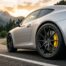 Étrier jaune et disque percé d'une Porsche grise sur une route de montagne